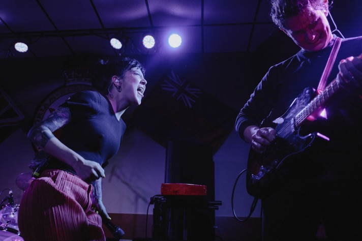 Michelle Zauner of the group Japanese Breakfast faces their guitar player and sticks their tongue out while performing at the #1 Royal Canadian Legion during Sled Island 2019.