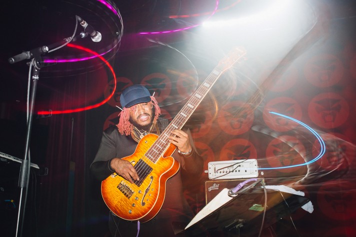 The artist Thundercat is seen playing an orange sunburst bass while on stage at The Palace Theatre during Sled Island 2018.
