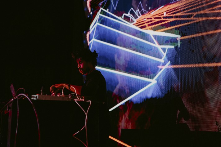 Electronic artist Flying Lotus is seen performing on stage at The Palace Theatre during Sled Island 2017. Blue and orange lasers shine behind them.
