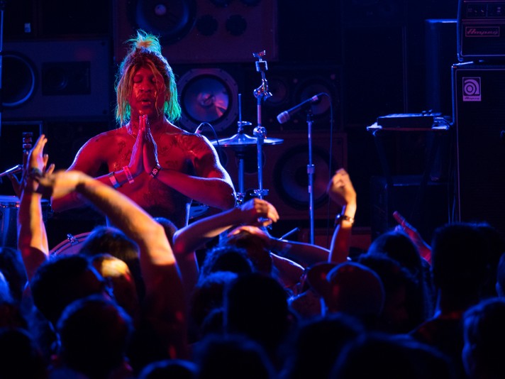 Artist Mykki Blanco is closing their eyes and holding their hands in a prayer position in front of an audience during their performance at Commonwealth Bar & Stage during Sled Island 2015.