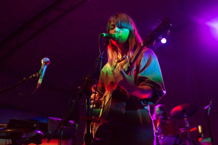 Artist Feist is shown playing guitar and singing bathed in colourful lights at Olympic Plaza during Sled Island 2012.