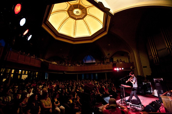 The artist Final Fantasy is shown playing violin in front of a full crowd at Central United Church during Sled Island 2009.