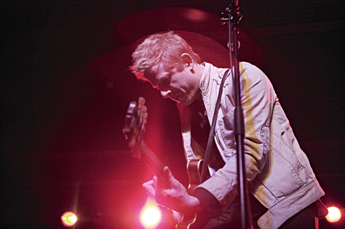 The frontperson for the band Spoon is shown playing guitar and wearing a denim jacket during their performance at MacEwan Hall for Sled Island 2007.