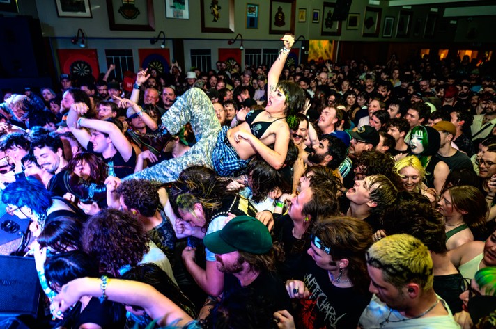 A festival-goer crowd surfs at the #1 Royal Canadian Legion during the Show Me the Body show at Sled Island 2024.
