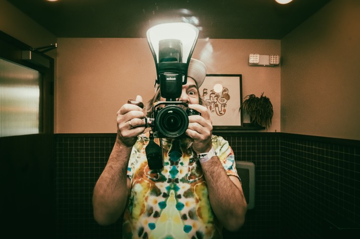A photographer takes a selfie in the bathroom during Sled Island 2024.