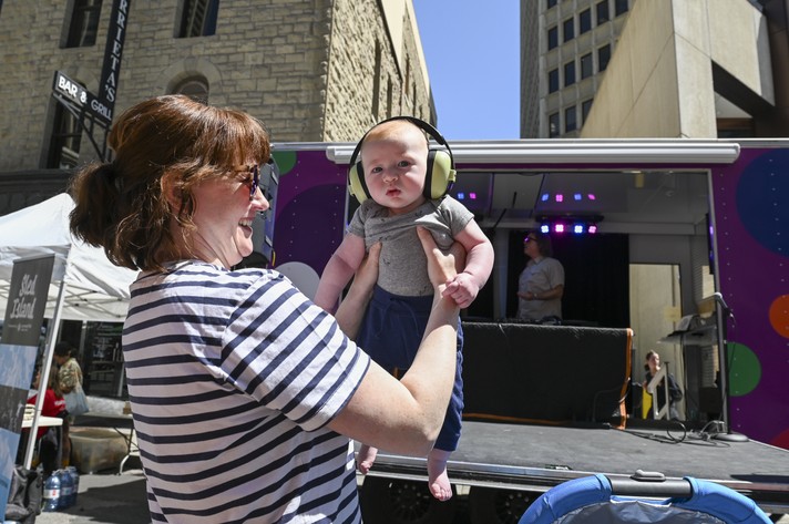A festival-goer holds up their baby wearing headphones at Sled Alley during Sled Island 2024.