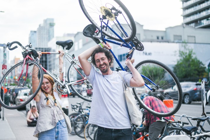 Two festival-goers hold up their bikes during Sled Island 2024.