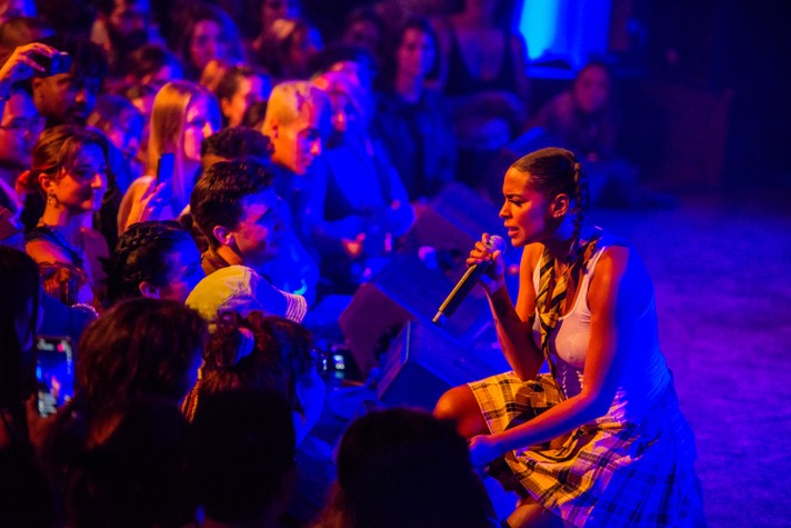 The artist Princess Nokia crouches down to sing face-to-face with the crowd during her performance at The Palace Theatre during Sled Island 2022.