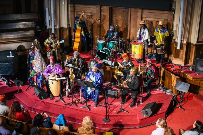 The group Sun Ra Arkestra are seen performing in bright, colourful outfits at Central United Church during Sled Island 2023.