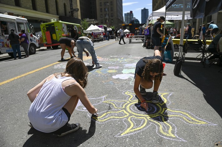 Kids draw on the street with sidewalk chalk at Sled Alley during Sled Island 2024.